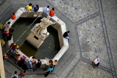 Люди сидят на фонтане "Нептун" на площади Рынок - вид сверху
